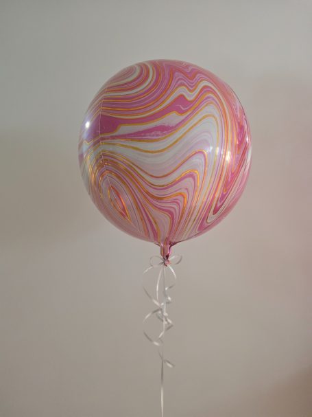 Rosa und weiße marmorierte Ballon schwebt an einem transparenten Band.