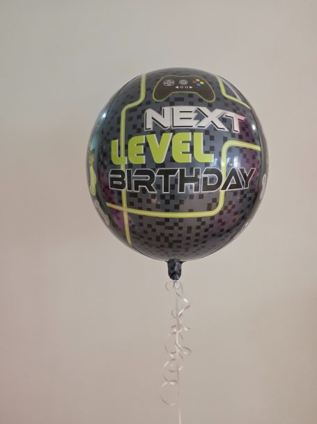 Schwarzer Ballon mit dem Aufdruck „NEXT LEVEL BIRTHDAY“ in leuchtenden Farben.
